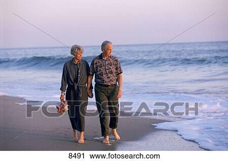 Stock Image - senior couple walking on the beach. Fotosearch