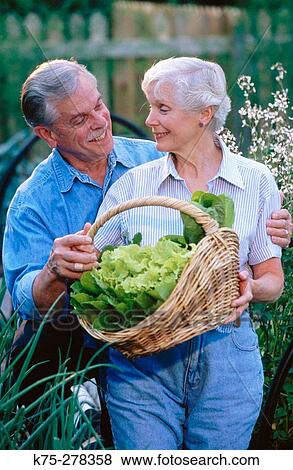 Stock Photo - Senior couple with basket of lettuce in garden. Fotosearch