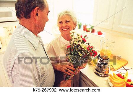 Senior couple with bouquet of flowers in kitchen View Large Photo Image Stock Image - Senior couple with bouquet of flowers in kitchen. Fotosearch