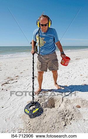 Senior male uses metal detector to find objects on a beach at Naples Florida View Large Photo Image Stock Photograph - Senior male uses metal detector to find objects on a beach at Naples Florida. Fotosearch
