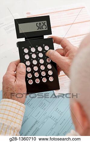 Stock Image - Senior Man calculating with a calculator in hand with medical and social security papers around him. Fotosearch