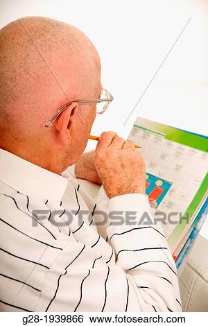 Senior man doing crossword in a magazine to exercise his memory and brain activity to avoid Alzheimer View Large Photo Image Stock Photograph - Senior man doing crossword in a magazine to exercise his memory and brain activity to avoid Alzheimer. Fotosearch