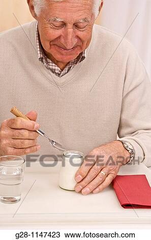 Senior man eating a yogurt View Large Photo Image Stock Image - Senior man eating a yogurt. Fotosearch