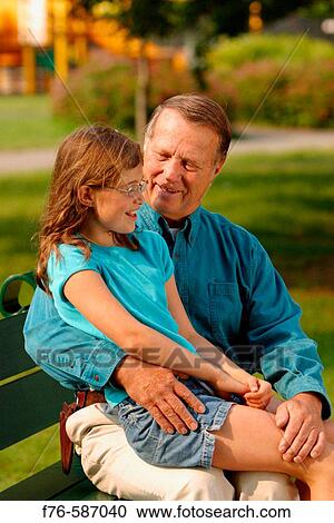 Senior man embracing his granddaughter while she is sitting on his lap. View Large Photo Image Stock Image - Senior man embracing his granddaughter while she is sitting on his lap.. Fotosearch