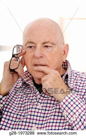 Senior Man head in chin holding spectacles, in a thoughtful puzzled mood View Large Photo Image Stock Photo - Senior Man head in chin holding spectacles, in a thoughtful puzzled mood. Fotosearch