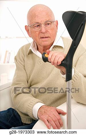 Senior man in a beige pullover, wearing glasses looking puzzled and holding his walking stick View Large Photo Image Stock Image - Senior man in a beige pullover, wearing glasses looking puzzled and holding his walking stick. Fotosearch