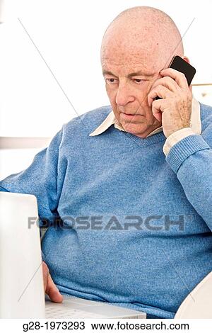 Senior man in a blue pullover using his phone and his laptop computer View Large Photo Image Stock Image - Senior man in a blue pullover using his phone and his laptop computer. Fotosearch