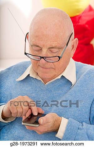 Senior man in a blue pullover, writing and sending a message on his phone, with his glasses on his nose View Large Photo Image Stock Image - Senior man in a blue pullover, writing and sending a message on his phone, with his glasses on his nose. Fotosearch