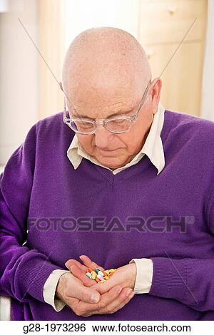 Senior man in a purple pullover thoughtful with a handful of medical tablets looking worried for overdose View Large Photo Image Stock Photograph - Senior man in a purple pullover thoughtful with a handful of medical tablets looking worried for overdose. Fotosearch