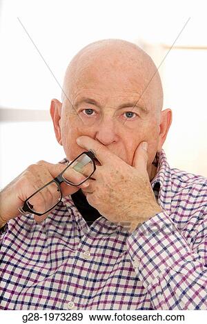 Senior man looking worried puzzled his hand in front of his mouth and holding glasses View Large Photo Image Stock Photo - Senior man looking worried puzzled his hand in front of his mouth and holding glasses. Fotosearch
