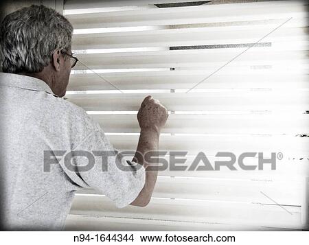 Senior man peering through the bars of the window. View Large Photo Image Picture - Senior man peering through the bars of the window.. Fotosearch