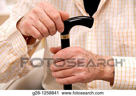 Stock Image - senior man? s hands resting on his walking stick. Fotosearch