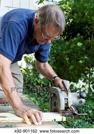 Senior man sawing wood View Large Photo Image Stock Image - Senior man sawing wood. Fotosearch