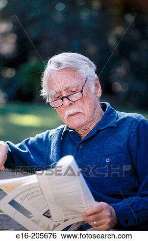 Senior man sitting on a bench reading a magazine View Large Photo Image Stock Photograph - Senior man sitting on a bench reading a magazine. Fotosearch