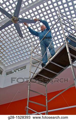 Senior man standing on scaffoldings to adjust a fan in his home View Large Photo Image Stock Image - Senior man standing on scaffoldings to adjust a fan in his home. Fotosearch
