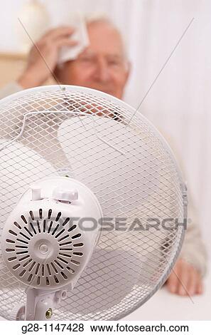 Senior man wiping his forehead with a fan, during hot period View Large Photo Image Stock Photo - Senior man wiping his forehead with a fan, during hot period. Fotosearch