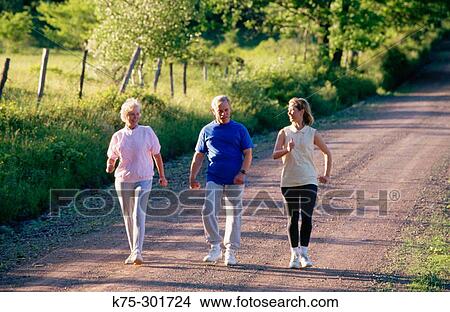 Picture - Senior parents walking with their adult daughter. Fotosearch