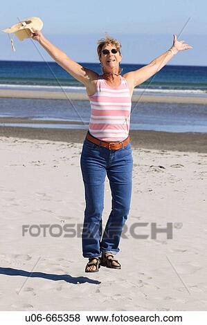 Senior woman 55 jumping for joy at the beach View Large Photo Image Stock Photo - Senior woman 55 jumping for joy at the beach. Fotosearch