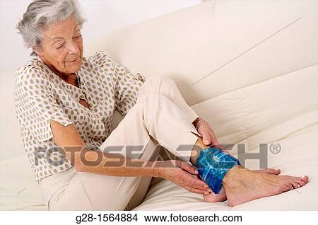 Senior woman applying a cold or hot gel compress on her ankle to soothe pain View Large Photo Image Picture - Senior woman applying a cold or hot gel compress on her ankle to soothe pain. Fotosearch