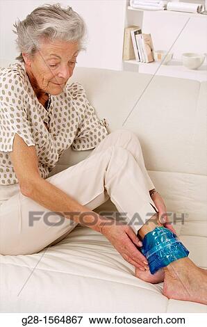 Senior woman applying a cold or hot gel compress on her ankle to soothe pain View Large Photo Image Stock Photo - Senior woman applying a cold or hot gel compress on her ankle to soothe pain. Fotosearch