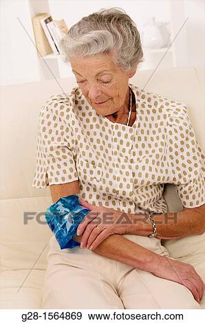 Senior woman applying a hot or cold gel compress to soothe elbow pain View Large Photo Image Stock Photo - Senior woman applying a hot or cold gel compress to soothe elbow pain. Fotosearch