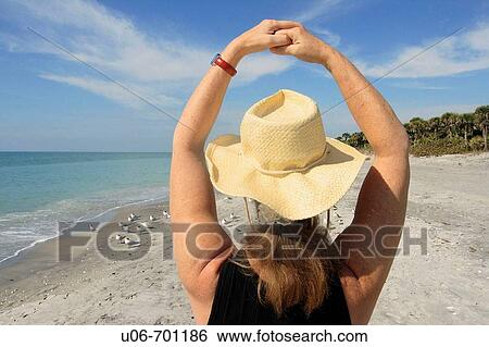 Stock Photograph - Senior woman at Casperson Beach in Venice (Florida, USA) with arms in a circle. Fotosearch