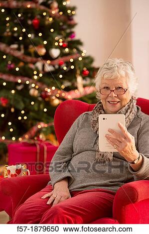Senior woman communicating with family on her tablet computer at Christmas time View Large Photo Image Stock Image - Senior woman communicating with family on her tablet computer at Christmas time. Fotosearch