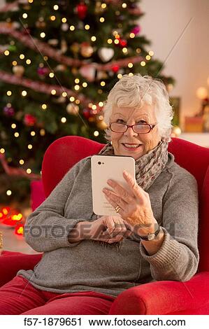Senior woman communicating with family on her tablet computer at Christmas time View Large Photo Image Stock Image - Senior woman communicating with family on her tablet computer at Christmas time. Fotosearch