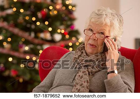 Senior woman communicating with family on her smart phone at Christmas time View Large Photo Image Stock Image - Senior woman communicating with family on her smart phone at Christmas time. Fotosearch