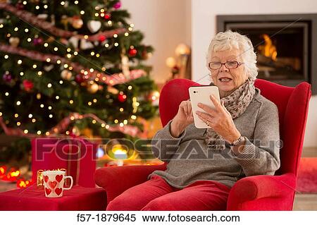 Senior woman communicating with family on her tablet computer at Christmas time View Large Photo Image Stock Photography - Senior woman communicating with family on her tablet computer at Christmas time. Fotosearch