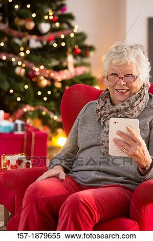 Senior woman communicating with family on her tablet computer at Christmas time View Large Photo Image Stock Photography - Senior woman communicating with family on her tablet computer at Christmas time. Fotosearch