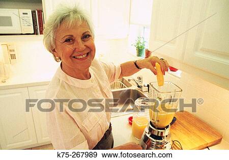 Senior woman fixes healthy beverage View Large Photo Image Stock Photo - Senior woman fixes healthy beverage. Fotosearch