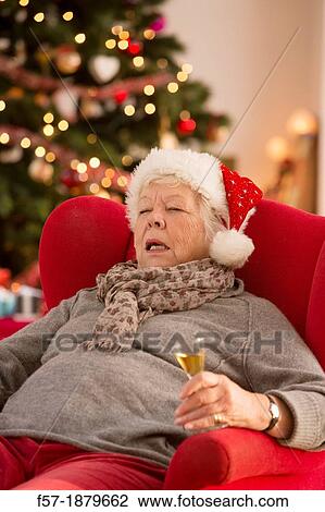 Stock Image - Senior woman having a catnap at Christmas time. Fotosearch