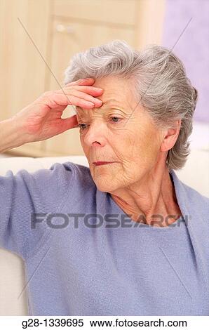 senior woman holding her forehead with a headache or not feeling well, wearing a mauve cardigan at home View Large Photo Image Stock Photography - senior woman holding her forehead with a headache or not feeling well, wearing a mauve cardigan at home. Fotosearch