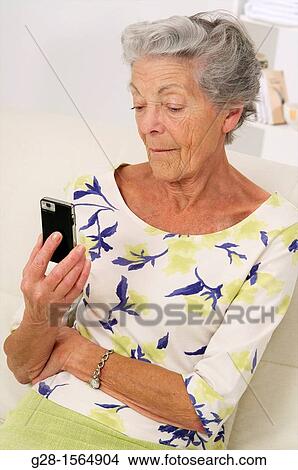 Senior woman holding her phone and reading a message View Large Photo Image Picture - Senior woman holding her phone and reading a message. Fotosearch