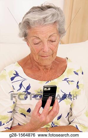 Senior woman holding her phone and reading a message View Large Photo Image Stock Photograph - Senior woman holding her phone and reading a message. Fotosearch