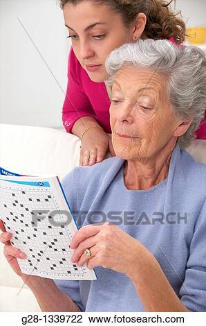 senior woman in a mauve cardigan, and young help playing crosswords together at home View Large Photo Image Stock Image - senior woman in a mauve cardigan, and young help playing crosswords together at home. Fotosearch