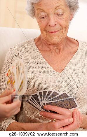 Stock Image - senior woman in beige playing cards with a young woman. Fotosearch