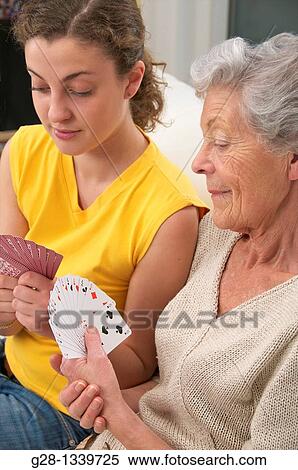 Stock Photography - senior woman in beige playing cards with a young woman at home. Fotosearch
