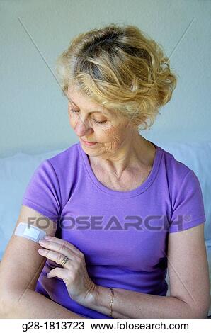 Senior woman in mauve putting a bandage on her arm View Large Photo Image Stock Image - Senior woman in mauve putting a bandage on her arm. Fotosearch