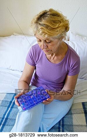 Senior woman in mauve, sitting on her bed, Holding a daily plastic distributor of pills View Large Photo Image Stock Photo - Senior woman in mauve, sitting on her bed, Holding a daily plastic distributor of pills. Fotosearch