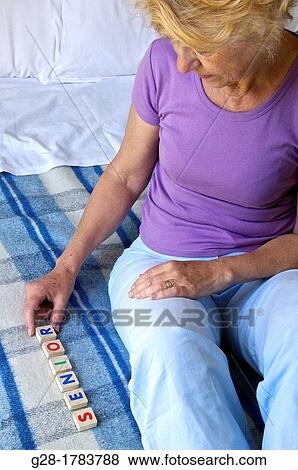 Senior woman on her bed writing the word Senior, with colored letters on her blanket, Alzeihmer problems View Large Photo Image Stock Photo - Senior woman on her bed writing the word Senior, with colored letters on her blanket, Alzeihmer problems. Fotosearch