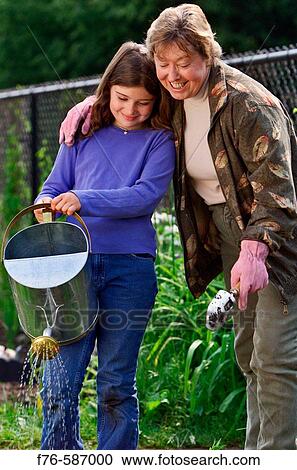 Senior woman planting flowers in garden with her granddaughter. View Large Photo Image Stock Image - Senior woman planting flowers in garden with her granddaughter.. Fotosearch