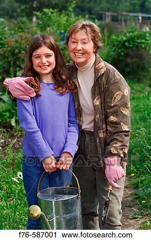Senior woman planting flowers in garden with her granddaughter. View Large Photo Image Stock Image - Senior woman planting flowers in garden with her granddaughter.. Fotosearch