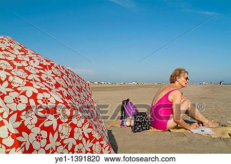 Senior woman reading a magazine at the beach, Camargue, France View Large Photo Image Stock Image - Senior woman reading a magazine at the beach, Camargue, France. Fotosearch