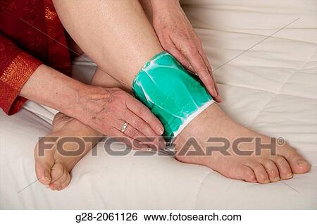 Senior woman? s hands applying a green cold or hot gel compress to relieve pain of a sprained ankle View Large Photo Image Stock Photograph - Senior woman? s hands applying a green cold or hot gel compress to relieve pain of a sprained ankle. Fotosearch