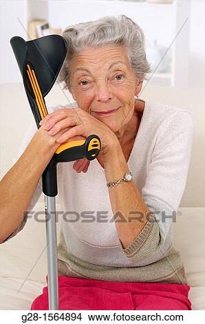 Senior woman smiling and thoughtful resting upon her crutches View Large Photo Image Picture - Senior woman smiling and thoughtful resting upon her crutches. Fotosearch