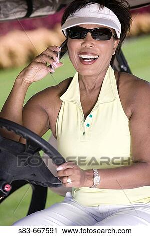 Senior woman talking on cellphone while driving golf cart View Large Photo Image Stock Image - Senior woman talking on cellphone while driving golf cart. Fotosearch