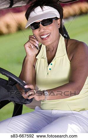Senior woman talking on cellphone while driving golf cart View Large Photo Image Stock Image - Senior woman talking on cellphone while driving golf cart. Fotosearch