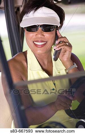 Senior woman talking on cellphone while driving golf cart View Large Photo Image Stock Image - Senior woman talking on cellphone while driving golf cart. Fotosearch